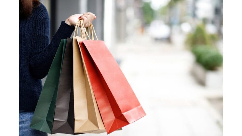femme qui fait du shopping, tenant 4 sacs à la main